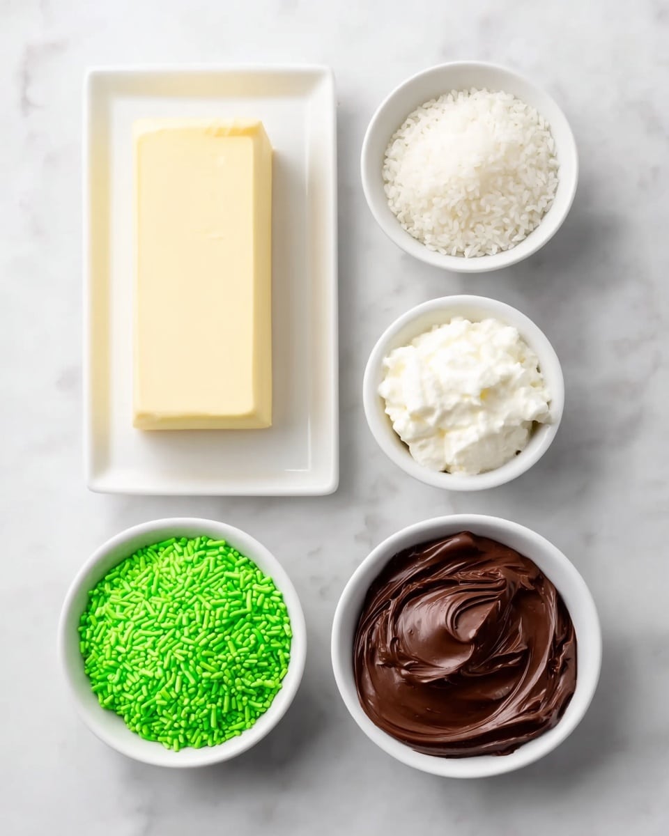 The image shows five small white bowls and a white rectangular plate arranged on a white marbled surface. The rectangular plate holds a solid block of pale cream butter. Around it, the top left bowl contains small white sprinkles, the top right bowl is filled with a fluffy, white cream, the bottom left bowl holds bright green sprinkles, and the bottom right bowl is filled with smooth dark brown chocolate spread. The bowls and plate are neatly arranged in a grid-like pattern. Photo taken with an iphone --ar 4:5 --v 7